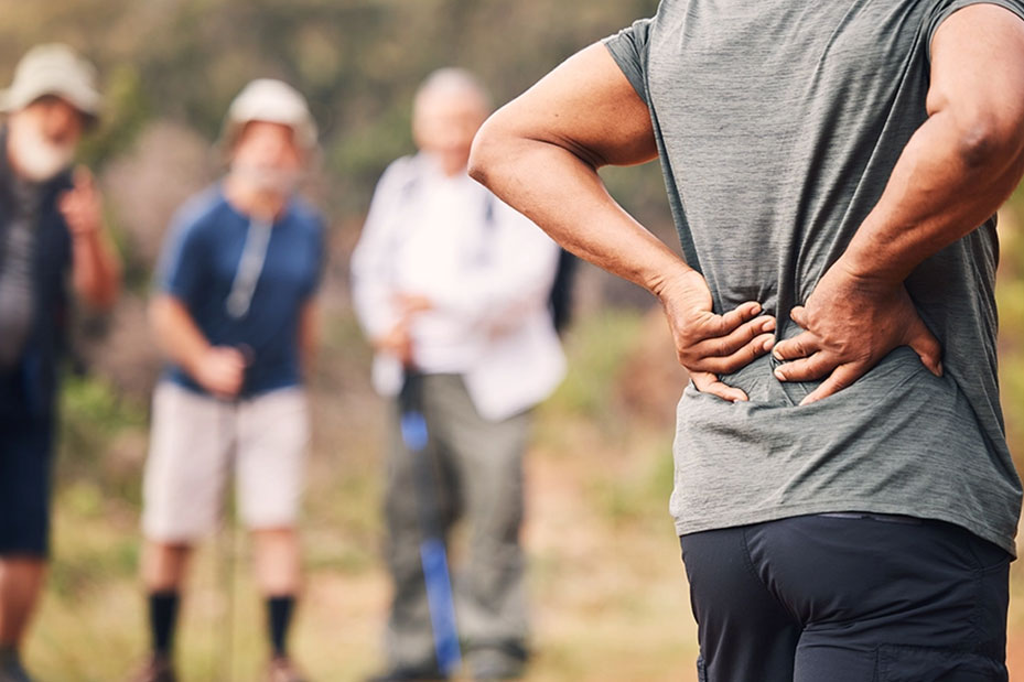 A man stands with his back to the camera, holding his lower back