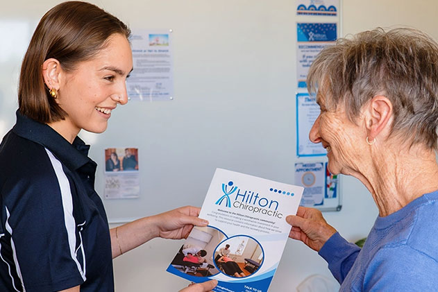 A woman displays a brochure, as an older woman looks on