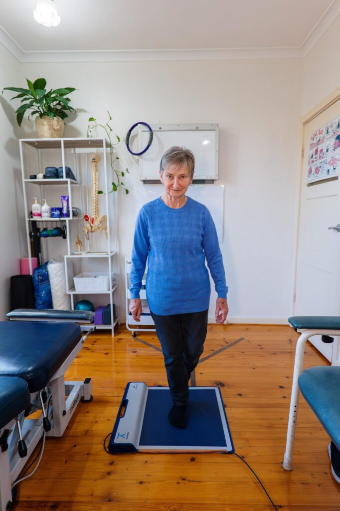 A woman stands on a mat in a well-lit room