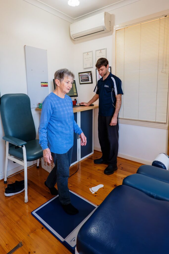 A woman stands beside a man in a well-lit room, both engaged in conversation.