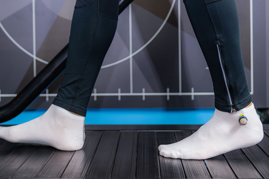 A person in black pants and white socks exercises on a treadmill
